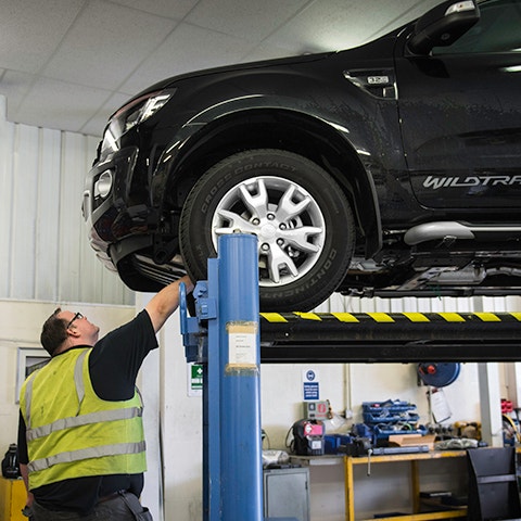 Vehicle on Lift with Fitter Looking Underneath